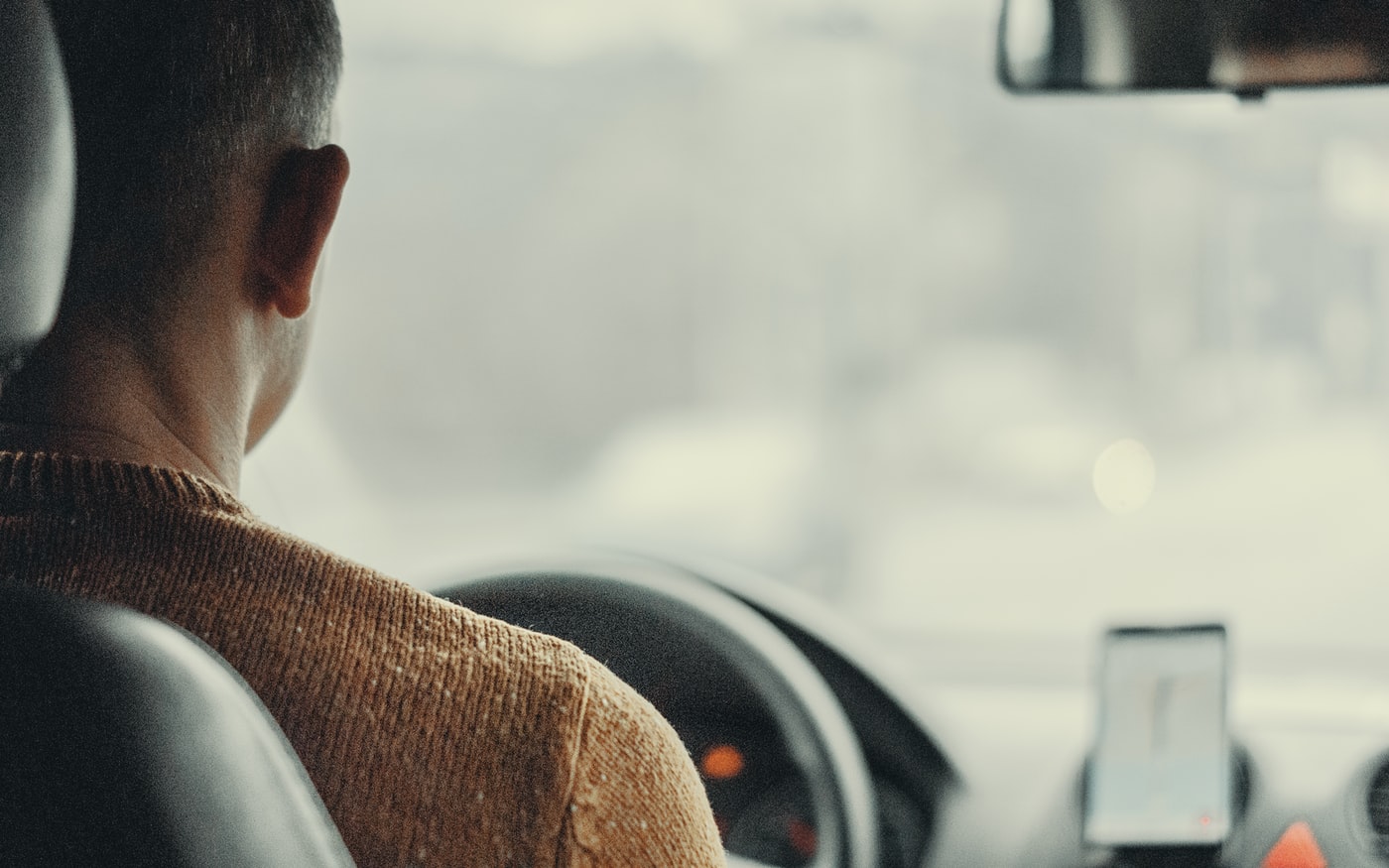 A driver with maps on a phone, over the shoulder